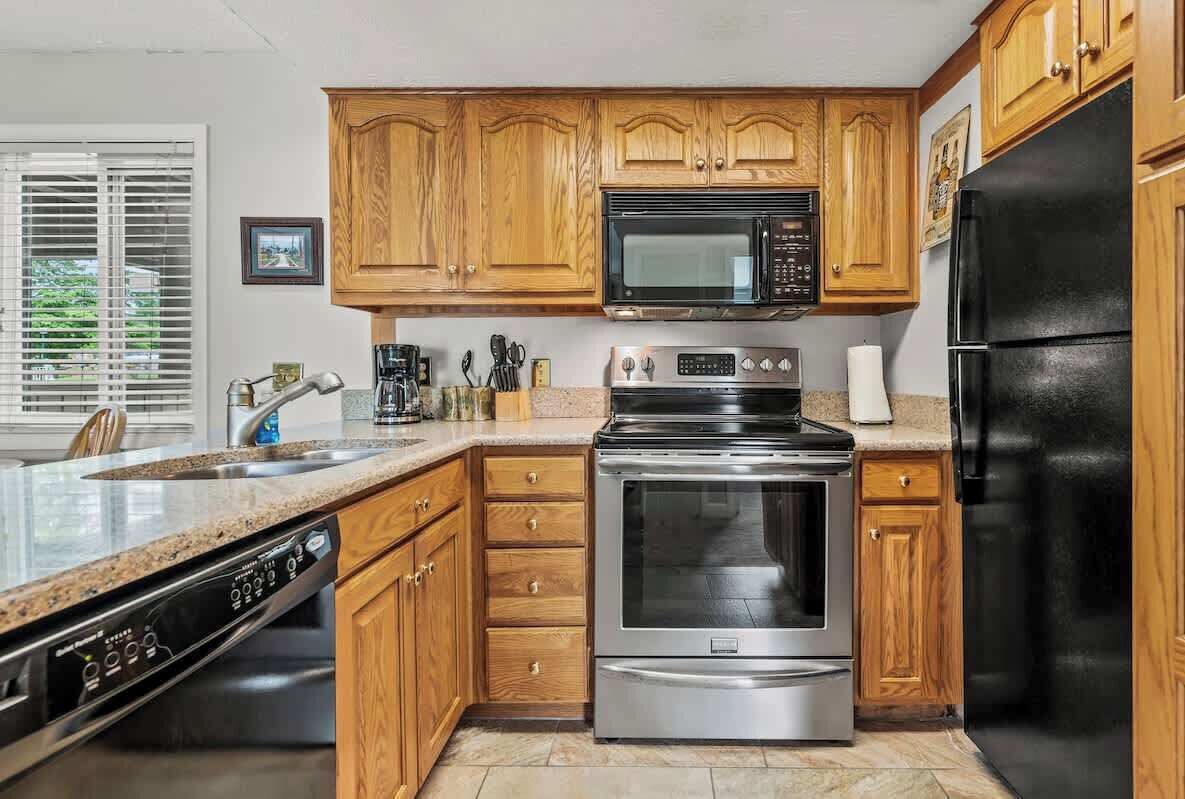 A kitchen with wooden cabinets, a stainless steel dishwasher, a microwave, a stove, and a refrigerator.