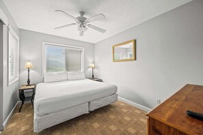 A bedroom with a bed, two bedside lamps, a ceiling fan, a wooden nightstand, a wooden dresser, and a mirror on the wall. - Mountain Views Indoor Pool Hot Tub Sleeps 4 (Gatlinburg)