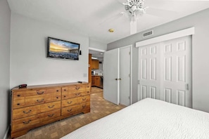 Un dormitorio con cama, cómoda de madera, un cuadro y armario.