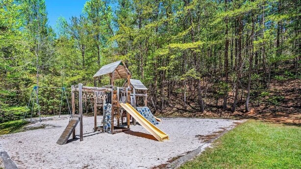 A wooden playground structure with a slide and swings, surrounded by a forested area. - Mountain Views Indoor Pool Hot Tub Sleeps 4 (Gatlinburg)