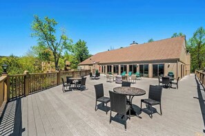 Eine überdachte Terrasse mit Tischen und Stühlen, ein Gebäude mit Ziegeldach und ein Geländer aus Holz.
