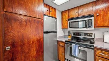A kitchen with wooden cabinets, a stainless steel refrigerator, a microwave, and an oven.