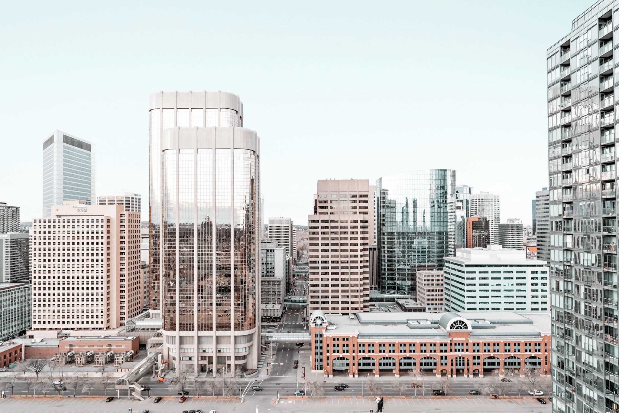 A cityscape with modern high-rise buildings, a prominent curved glass structure, and a historic building with arched windows.