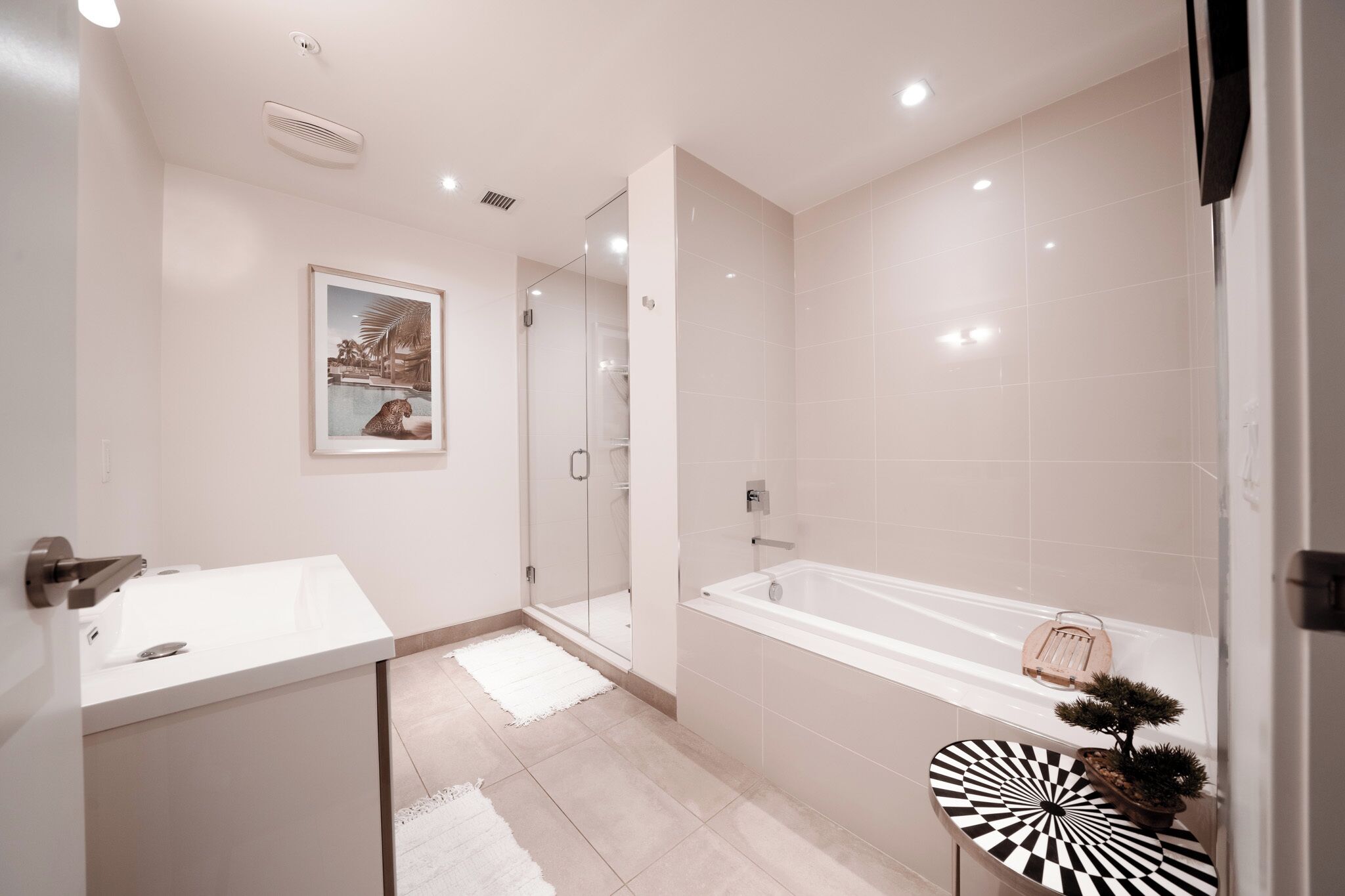 A modern bathroom with a white sink, a bathtub, and a glass shower enclosure.