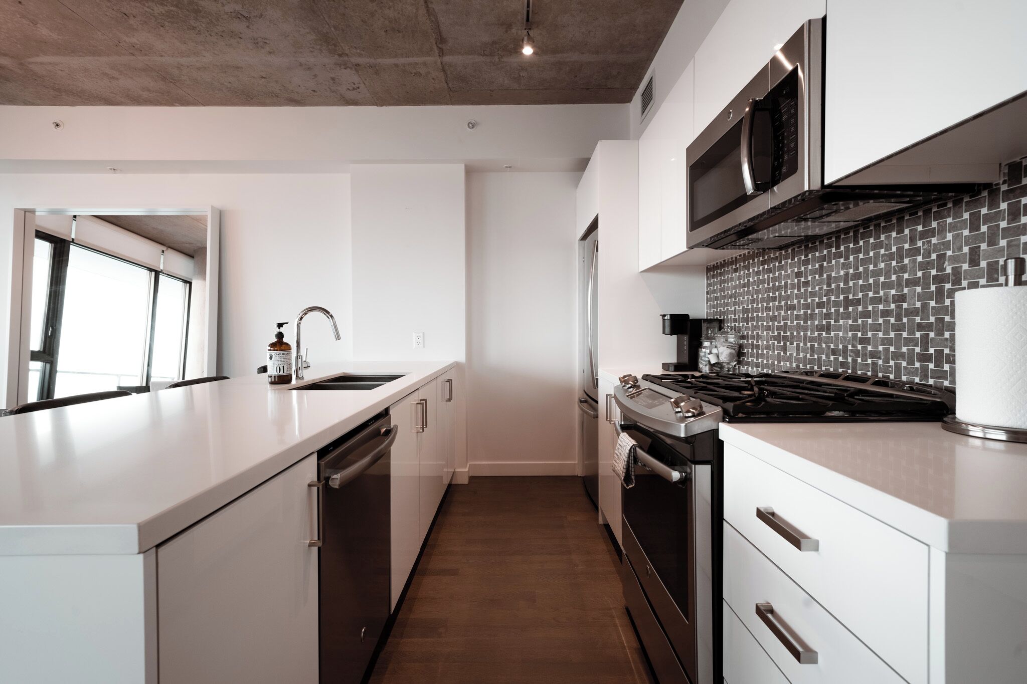 Una cocina moderna con armarios blancos, una campana de acero inoxidable y un salpicadero de azulejos.