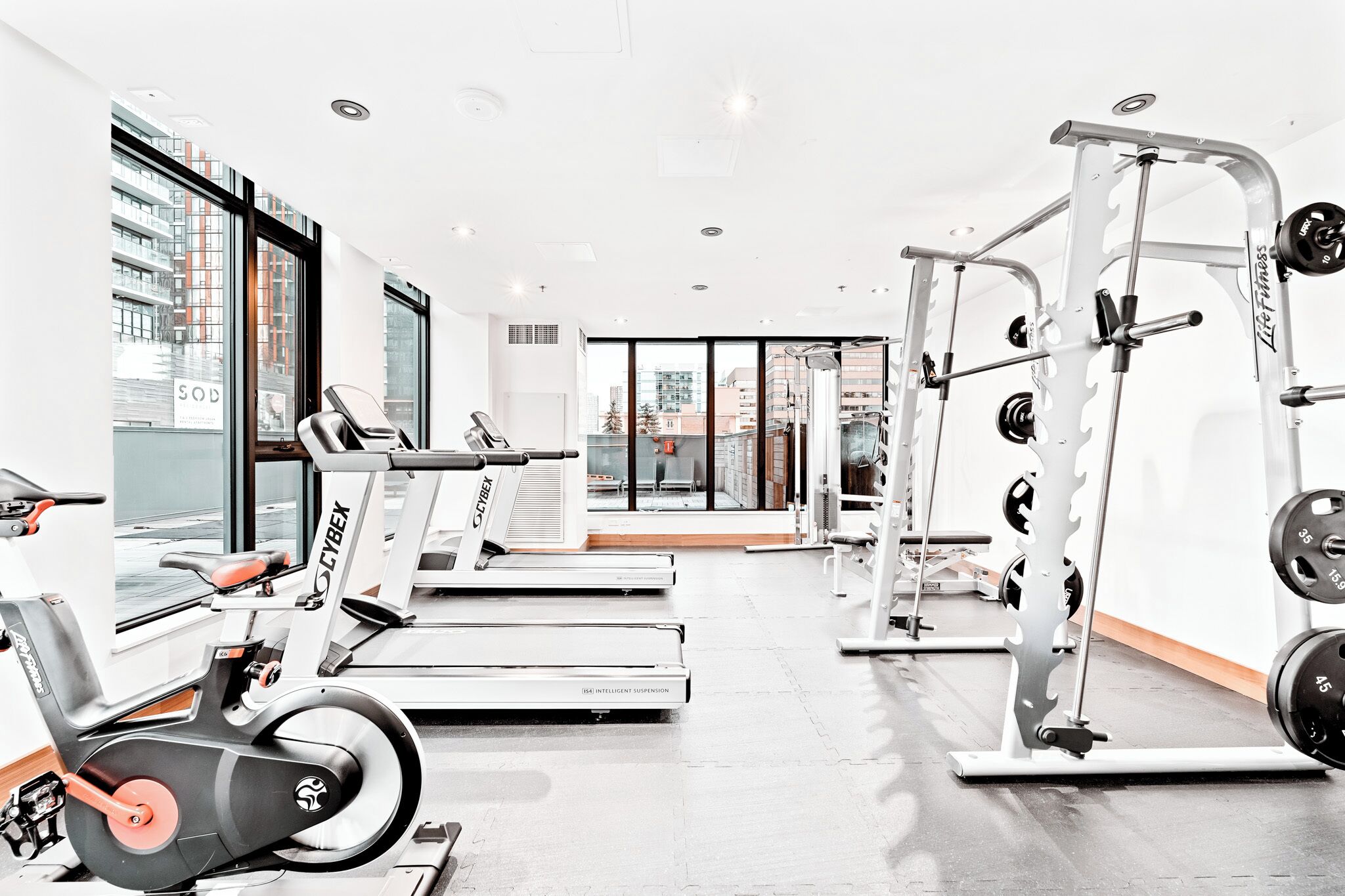 Une salle de sport équipée de tapis de course, d’un appareil elliptique et de matériel de musculation.