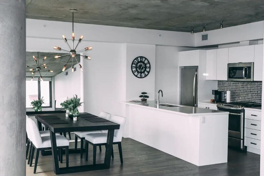 Una cocina moderna con armarios blancos, un refrigerador de acero inoxidable y un microondas empotrado.