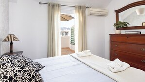 Ett hotellrum med en säng, en byrå, en lampa och utsikt över omgivningarna.