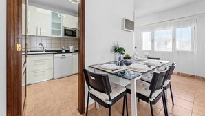 A modern kitchen with white cabinets and a dining area with a glass table and black chairs.