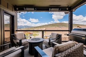 A balcony with wicker furniture, a grill, and a view of mountains. - Wellness Retreat with Fitness Equipment, Sauna, Cold Plunge and Hot Tub (Kamas)