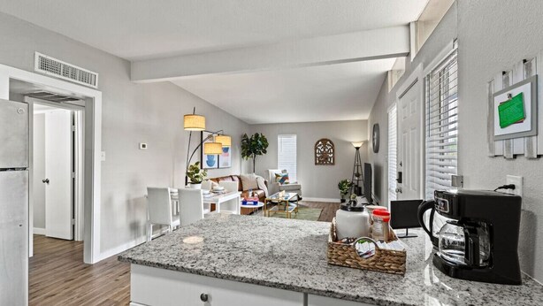Eine moderne Küche mit Granit Arbeitsplatten, einer Kaffeemaschine und einem Essbereich mit Sofa und Tisch.