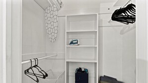 Ein weißer Schrank mit Regalen, einer Kleiderstange und einem Wäscheständer.