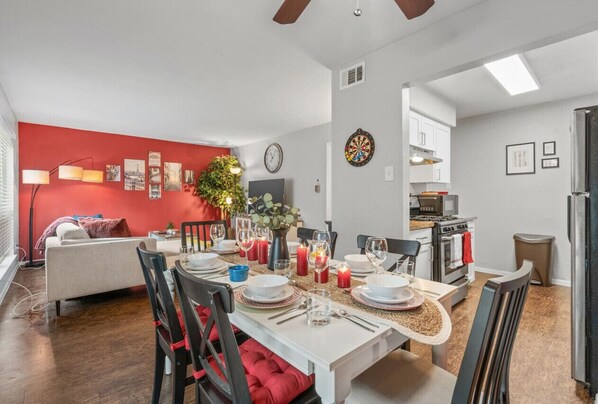 Un espace de vie moderne comprenant un coin repas, une cuisine et un mur d’accent de couleur rouge.