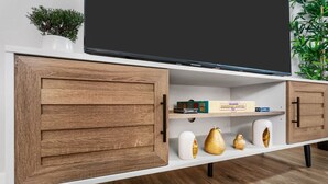 Un mueble moderno de entretenimiento con un televisor de pantalla plana, armarios de madera y objetos decorativos.