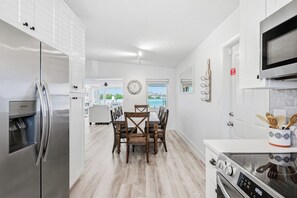 A modern kitchen with a refrigerator, stove, microwave, and dining area with chairs and a table.