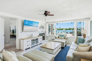 Un salon spacieux doté d’un ventilateur de plafond, d’un grand téléviseur et offrant une vue sur l’océan.