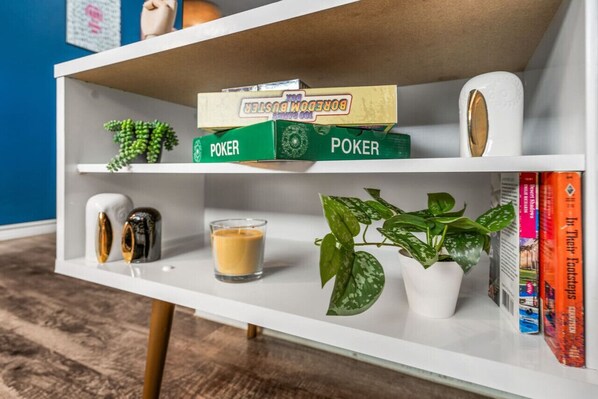 Una estantería con libros de póker, una vela y una planta en maceta.