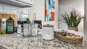 A kitchen counter with various items including olive oil, coffee mugs, and a coffee pot. - Where It's All Happening: 1BD in the Mid of Action (Arlington)