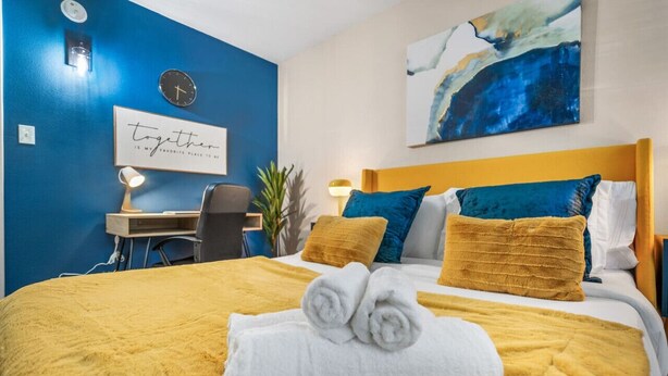 A hotel room with a bed, a desk, a chair, and a wall clock. - Where It's All Happening: 1BD in the Mid of Action (Arlington)