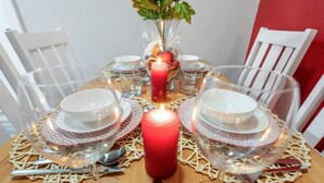 A dining table set with white plates, clear glassware, and a lit red candle centerpiece. - Steps Away from the Heart of the FUN!AT&T Walkable (Arlington)
