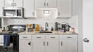 A kitchen with white cabinets, a microwave, a stove, and various kitchen appliances. - Blissful 1BD:AT&T Walkable, Modern & Ground-Level! (Arlington)