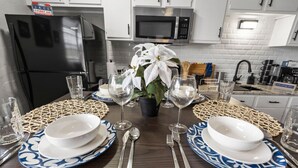 A dining table set with white and blue plates, silverware, and wine glasses, surrounded by a woven placemat. - Blissful 1BD:AT&T Walkable, Modern & Ground-Level! (Arlington)