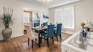 A dining area with a wooden table, blue upholstered chairs, and a vase with flowers. - Uplifting 2BD: Centered, Inspiring & Heartwarming! (Fort Worth)