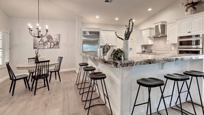 A modern kitchen with white cabinets, a marble island, and bar stools.
