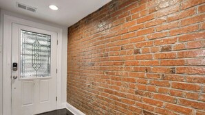 Ein Flur mit einer weißen Tür, die ein Glasschiebepaneel und eine Backsteinwand aufweist.