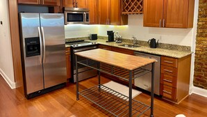 Eine moderne Küche mit Holzschränken, Edelstahlgeräten, Granit Arbeitsplatten und einem eingebauten Backofen.