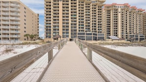 A boardwalk leading to a high-rise hotel with multiple balconies and a beach view. - GULF-FRONT CONDO, POOLS, SPLASH PAD, LOTS OF AMENITIES! (Orange Beach)