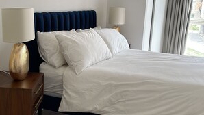A modern hotel room with a large bed, two bedside tables, and a window with curtains. - Modern apartment in the heart of London.  (London)