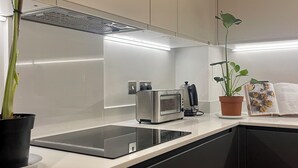 A modern kitchen with a built-in oven, a coffee machine, and a potted plant. - Modern apartment in the heart of London.  (London)