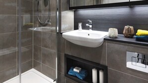 A modern bathroom with a glass shower enclosure, a white sink, and a mirror above it. - Modern apartment in the heart of London.  (London)