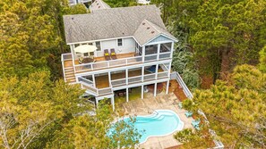 A multi-story house with a swimming pool, surrounded by dense trees. - Smoothie Sailing | Pool, Hot Tub & Easy Beach (Corolla)