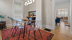 A dining area with a glass table, clear chairs, a red patterned rug, and a chandelier. - Stunning Townhouse in an Amazing Location Near Fiserv, Baird Center, Lakefront (Milwaukee)