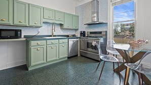 A modern kitchen with green cabinets, stainless steel appliances, and a glass dining table. - Stunning Townhouse in an Amazing Location Near Fiserv, Baird Center, Lakefront (Milwaukee)