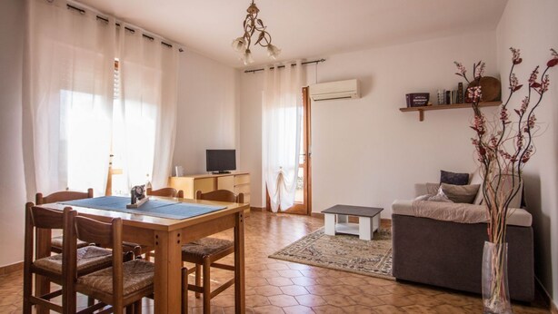 Una sala de estar con un sofá, una mesa de centro, un televisor y un comedor con sillas y una mesa.