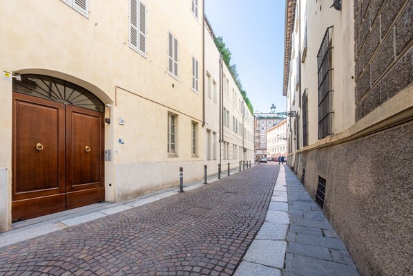 Una estrecha calle adoquinada bordeada por edificios con puertas y ventanas de arco.