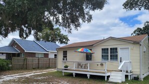 A single-story house with a front porch, a small deck, and a colorful umbrella.