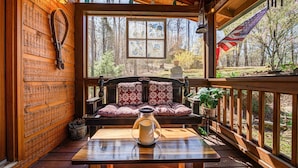 A wooden cabin with a wooden bench and table, a stained glass window, and an American flag. - Peaceful Blue Ridge Mtn Cabin-Gated, WiFi, Hot Tub, Fire Pit, Game Room (Blue Ridge)