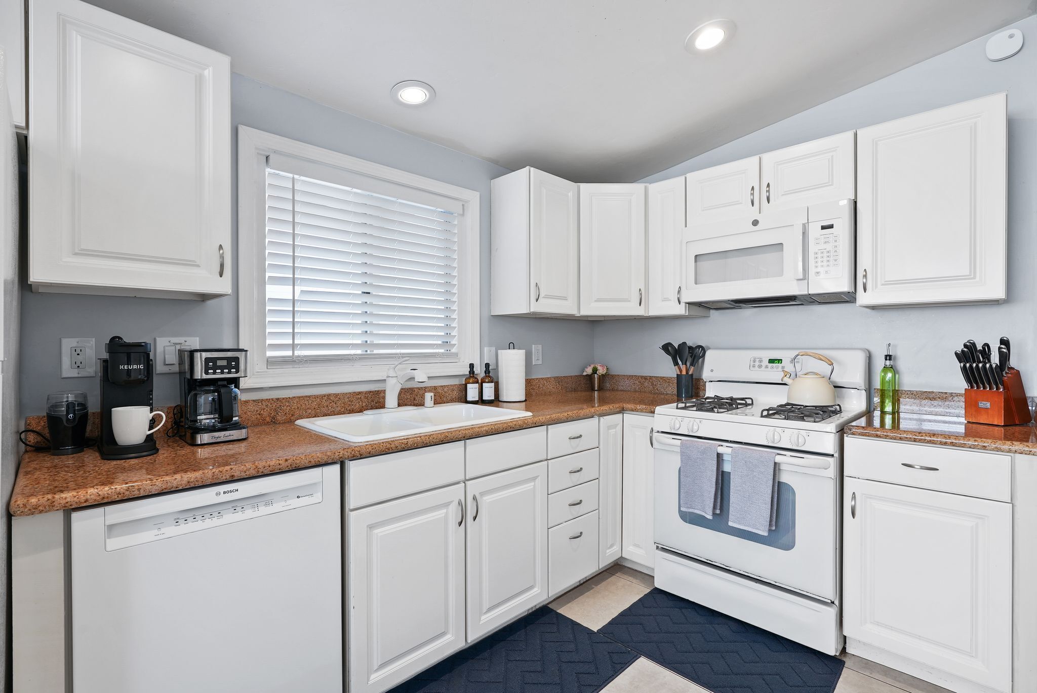 A modern kitchen with white cabinets, a built-in microwave, a stove, and a dishwasher.
