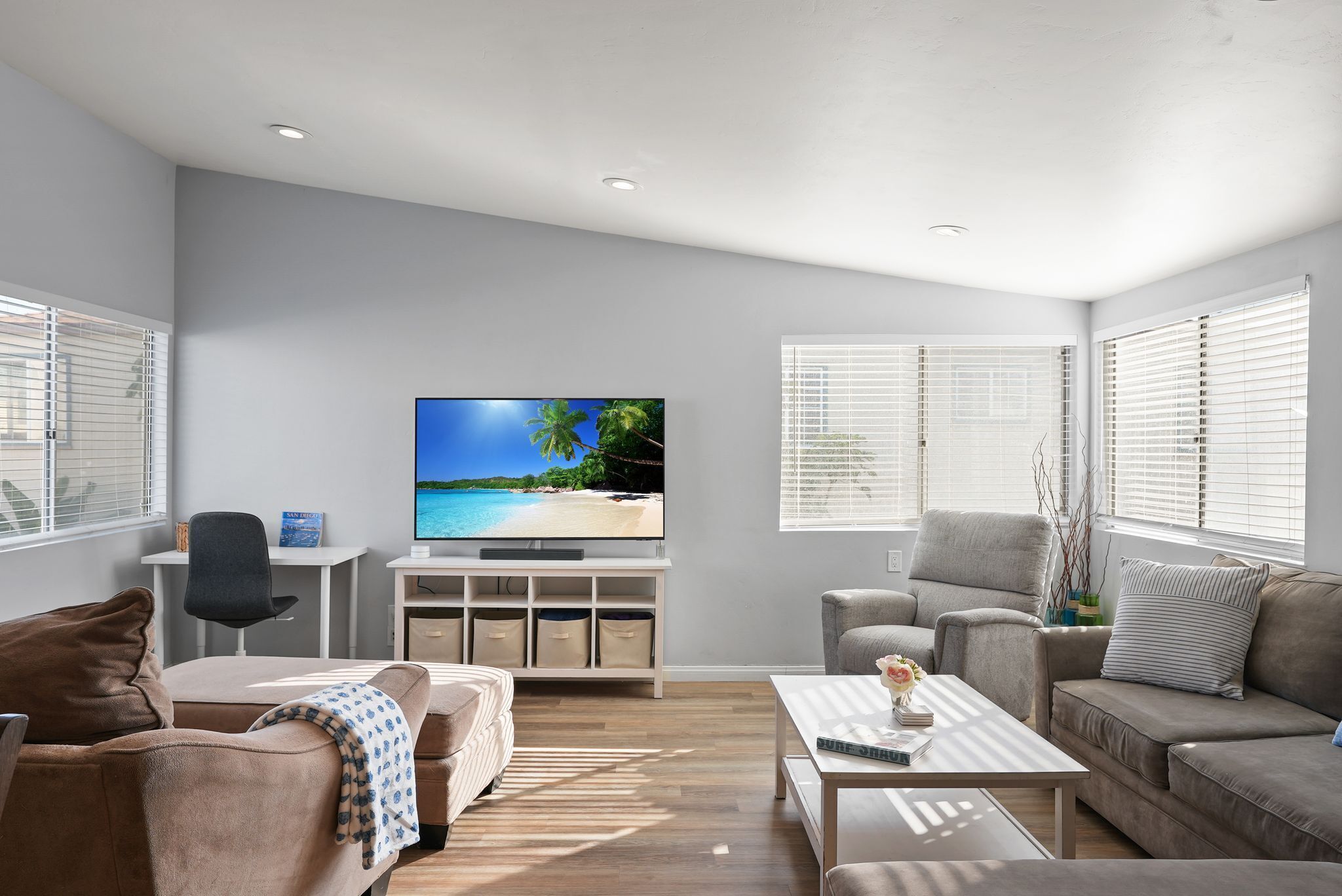 A modern living room with a flat-screen TV, two sofas, a coffee table, and a TV stand with storage.