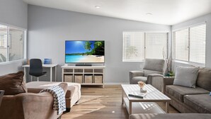 Un salon moderne doté d’un téléviseur à écran plat, de deux canapés, d’une table basse et d’un meuble TV avec espace de rangement.