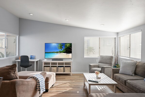 A modern living room with a flat-screen TV, two sofas, a coffee table, and a TV stand with storage.