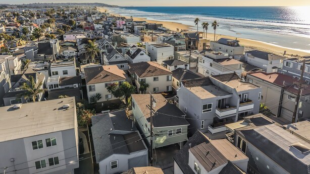 Une zone résidentielle côtière avec des maisons, une plage et un ciel dégagé.