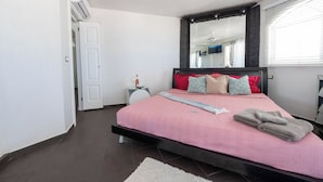 A bedroom with a bed, bedside table, and a mirror.