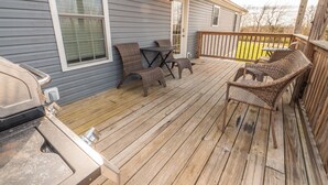 Una terraza cubierta con mobiliario exterior, ventilador de techo y una parrilla.