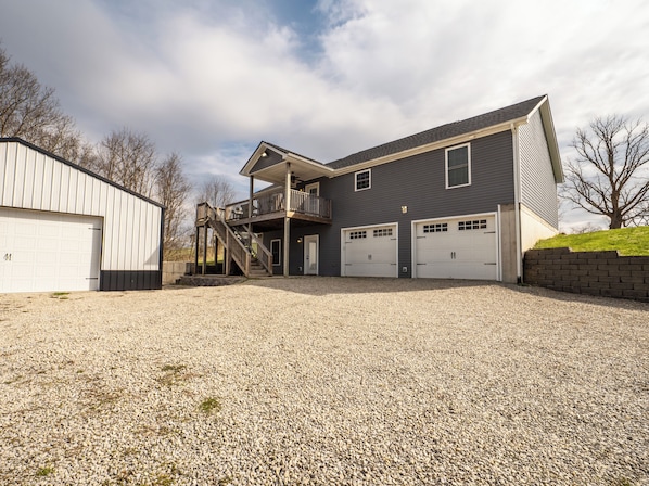 A two-story house with a covered porch, a gravel driveway, and two garage doors.
