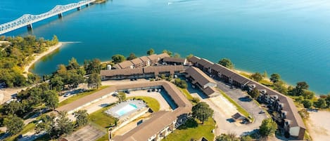 Luchtbeeld van een hotel met een zwembad, omringd door groen, met een brug op de achtergrond.